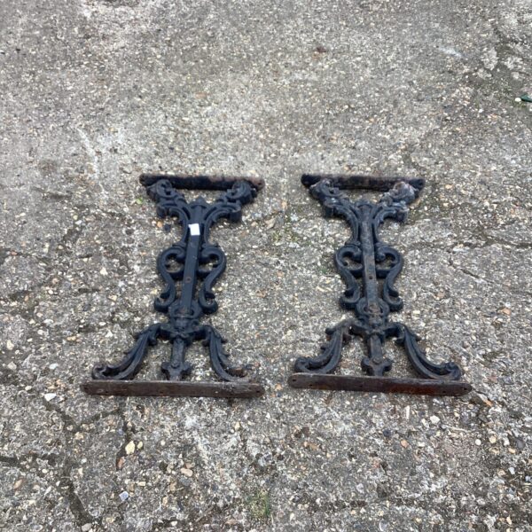 Pair of antique wrought iron garden table legs with ornate design.