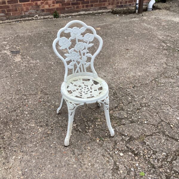 White metal garden chair with detailed floral design.