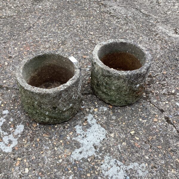 Weathered concrete garden planters on a textured surface.