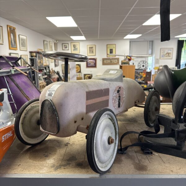 Side view of a vintage metal ride-on car.