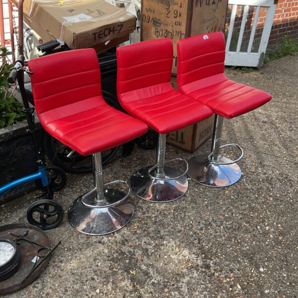 Three red cushioned bar stools in a kitchen setting.