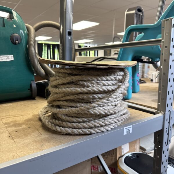 Thick coir rope wound on a wooden reel for nautical or industrial use.