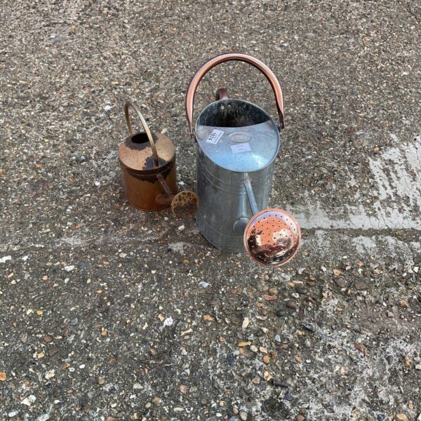 Pair of vintage galvanised watering cans for garden use.