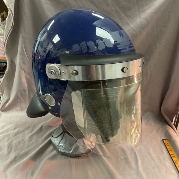 Front view of a used police riot helmet with face shield.