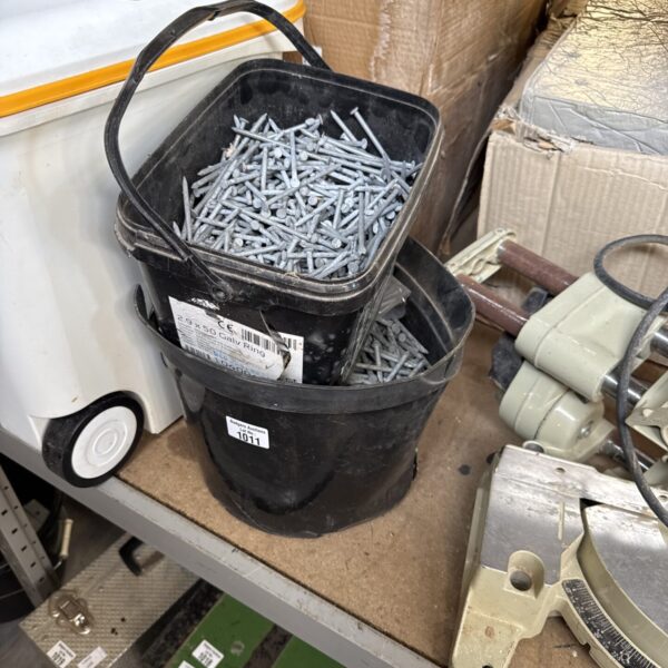 Two buckets filled with large steel nails for construction projects.