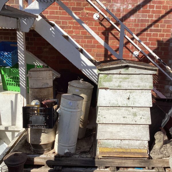 Vintage beehive and beekeeping equipment in a garden setting.