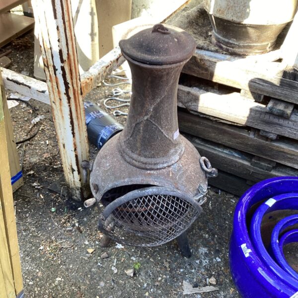 Vintage metal garden chiminea with mesh front and weathered patina.