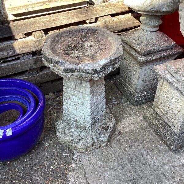 Weathered stone bird bath in a garden setting.