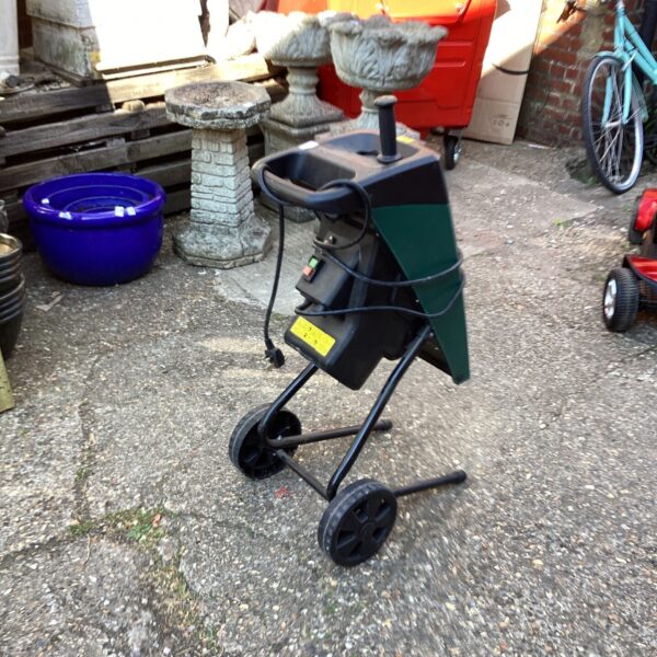 Side view of an electric garden shredder in a garden setting.