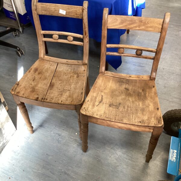 Pair of antique wooden kitchen chairs with weathered finish.