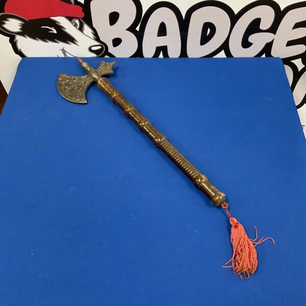 Detailed ornamental wall axe with red tassel.
