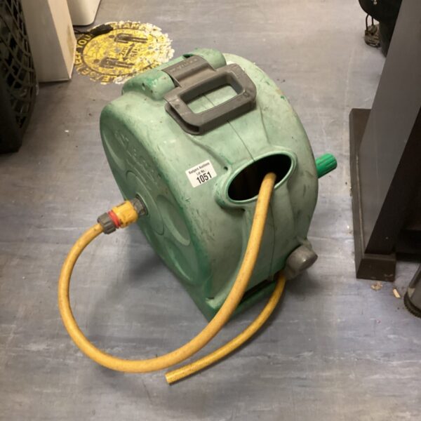Green Hozelock hose reel in a garden setting.