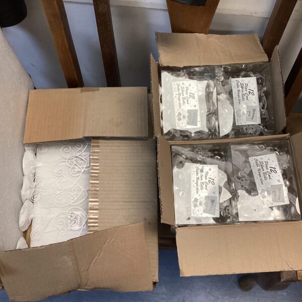 Three boxes of silver bell place card holders for wedding table settings.