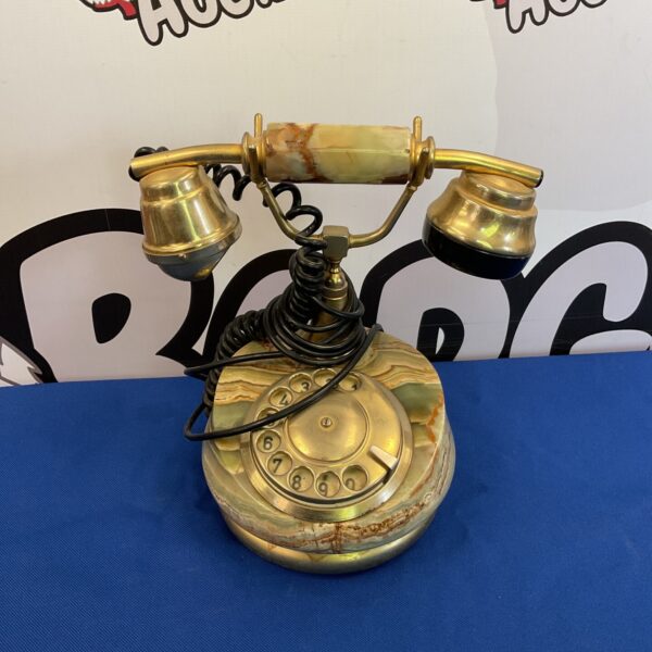 Close-up of a vintage marble rotary telephone with brass details.