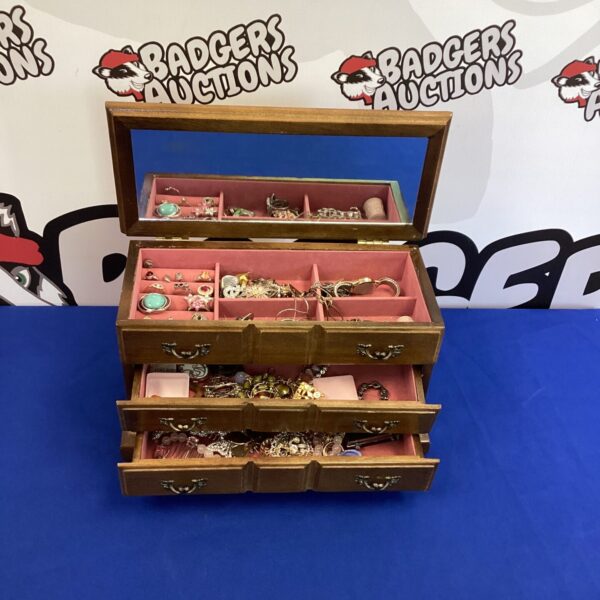 Open vintage wooden jewellery box filled with jewellery.