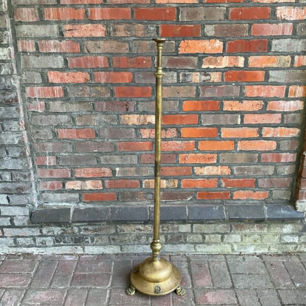 Antique brass church floor candlestick with clawed feet.