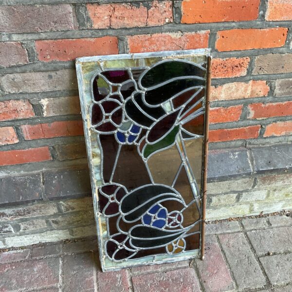 Vintage stained glass window with a vibrant floral design and lead came.