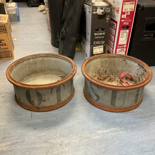 Two large vintage galvanised planters in a garden setting.