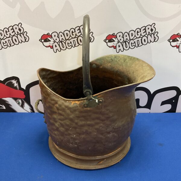 Vintage copper coal scuttle with wooden handle for fireplace use.