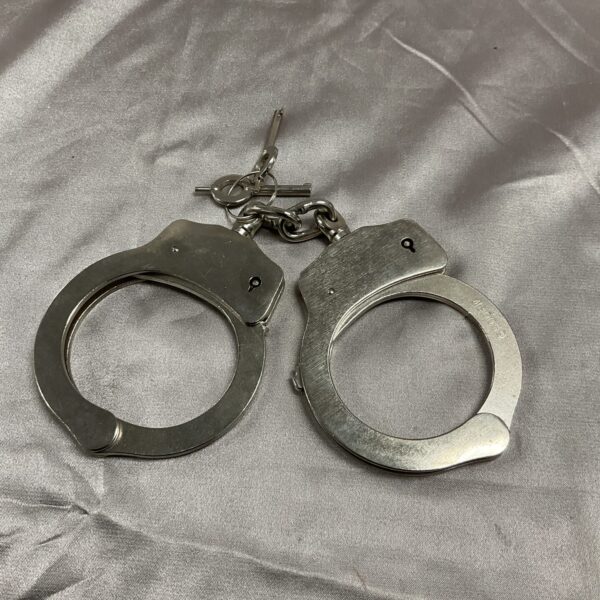 Vintage metal handcuffs with key, antique security restraints.