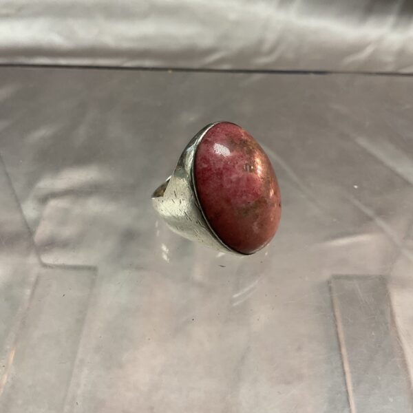 Close-up of a silver ring with a pink rhodochrosite gemstone.