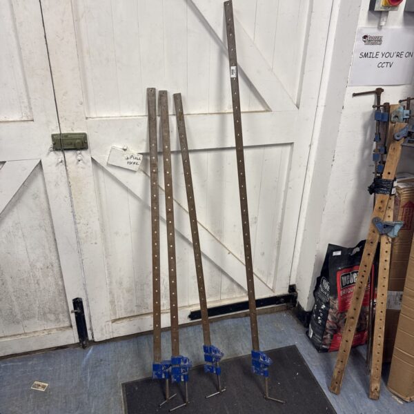 Four large metal sash clamps for woodworking projects.