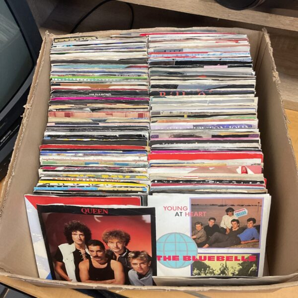 Collection of vintage 7-inch vinyl singles including Queen and Huey Lewis.
