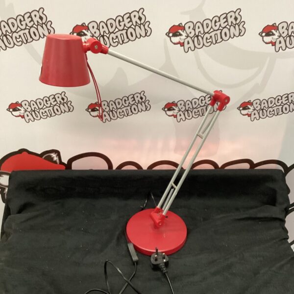 Vintage red adjustable reading lamp on a dark surface.