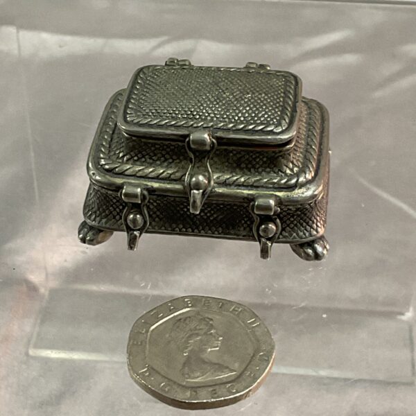 Antique silver two-tier pill box on a reflective surface.