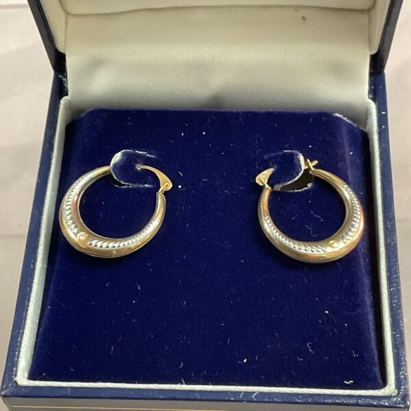 Polished 9ct gold hoop earrings on a display cushion.