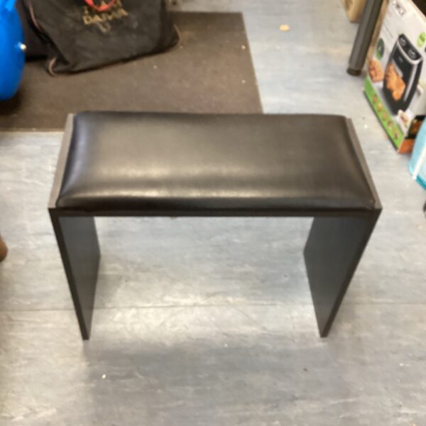 Black piano stool with wooden legs, side view.