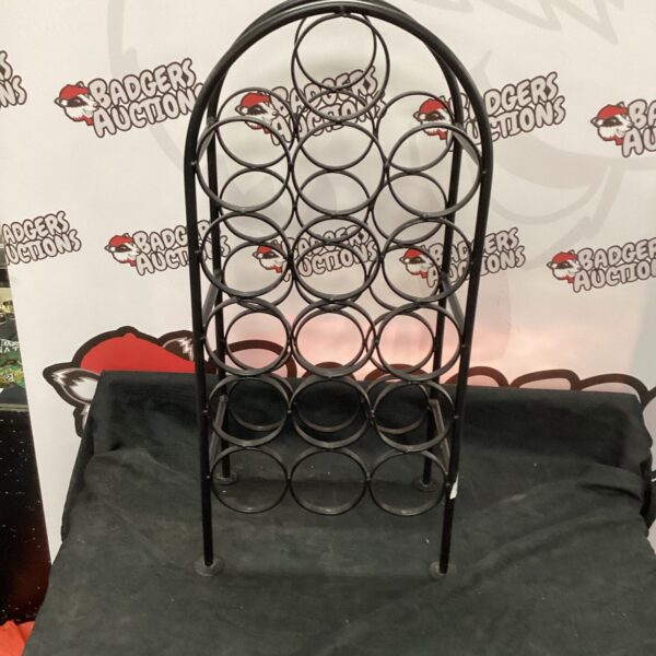 Dark metal wine rack with circular bottle openings.
