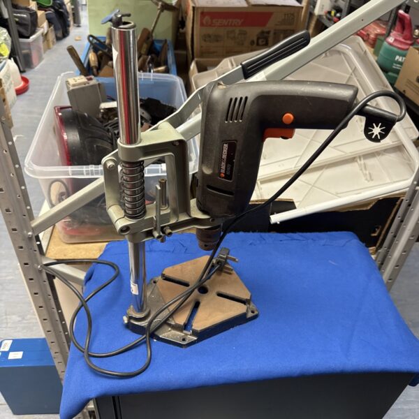 Vintage Black & Decker drill stand on a workbench.
