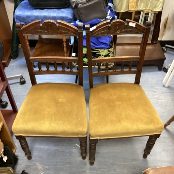 Antique chair pair with patterned upholstery and carved wood.