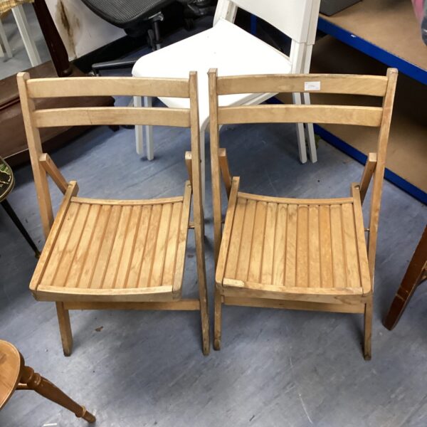 Pair of vintage wooden folding chairs in natural wood finish.