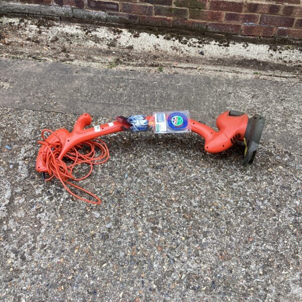 Used electric garden strimmer with power cable for lawn maintenance.