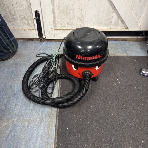 Red Numatic Henry NV200 cylinder vacuum cleaner with hose.