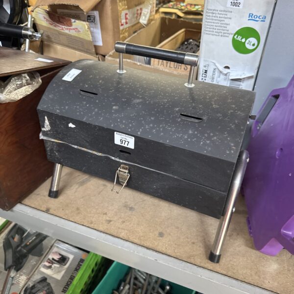 Small charcoal barbecue on legs, ready for outdoor cooking.