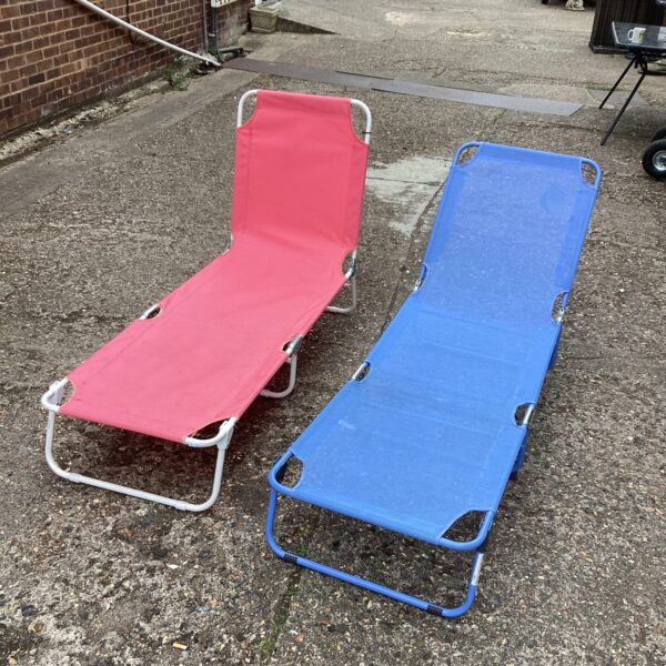 Two vintage sun loungers in a garden setting.