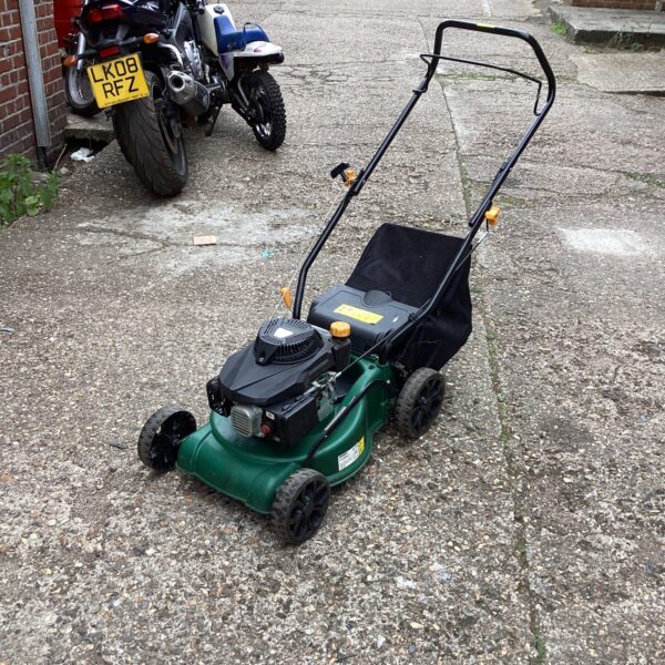 Green FPLM 99-3 petrol lawn mower in a garden setting.