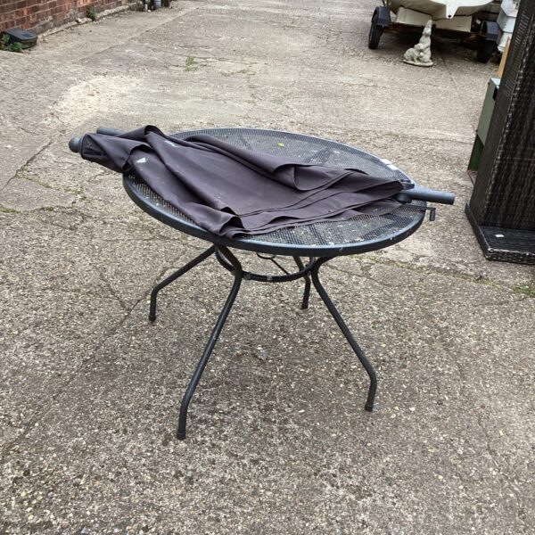 Metal garden table with umbrella in a garden setting.