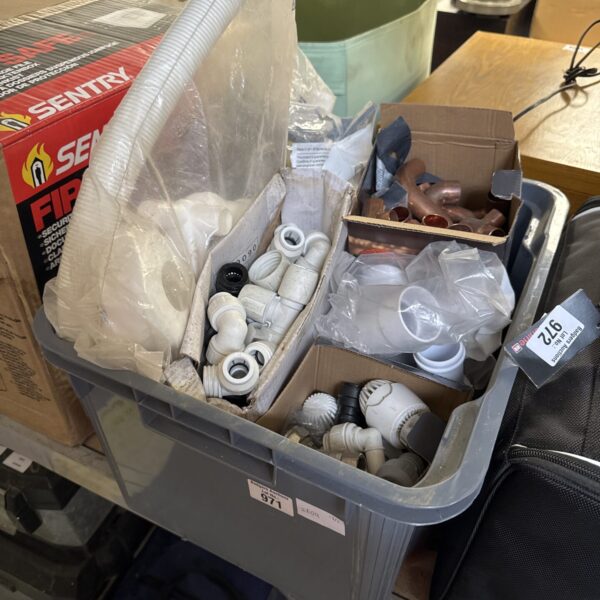 Assorted plumbing fittings and PVC pipe connectors in a box.