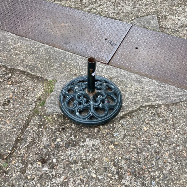 Decorative metal parasol base for garden or patio use.