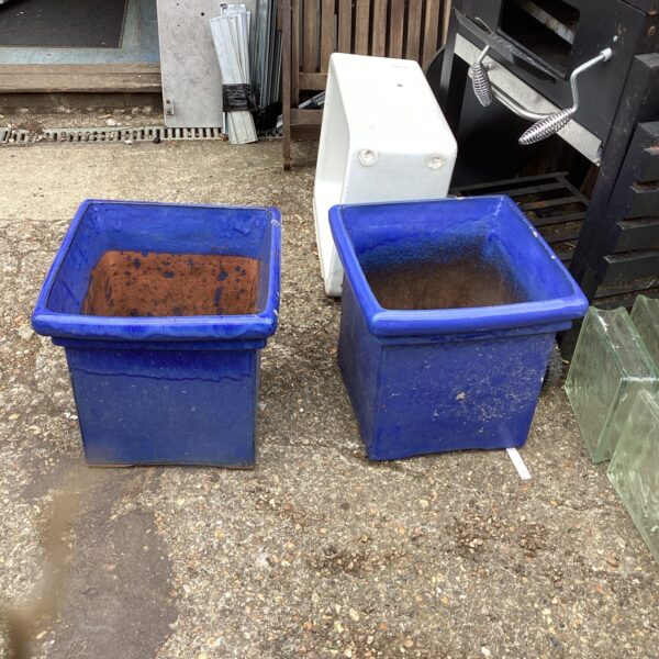 Vibrant blue glazed garden tubs, one with a crack, for outdoor planting.