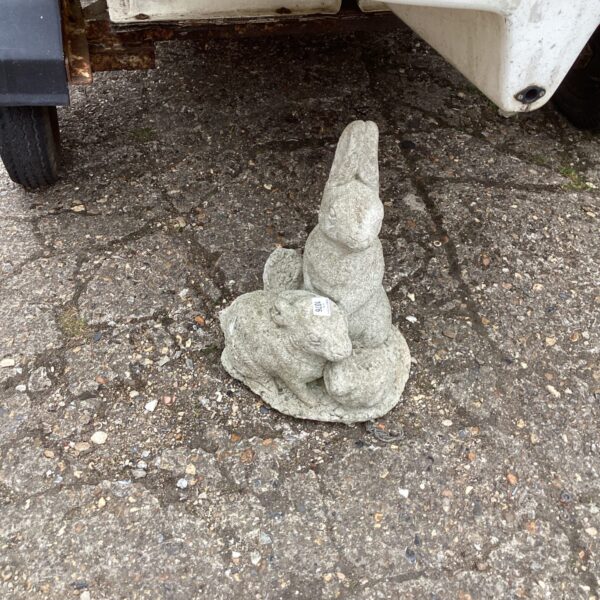 Concrete garden rabbit ornament in a garden setting.