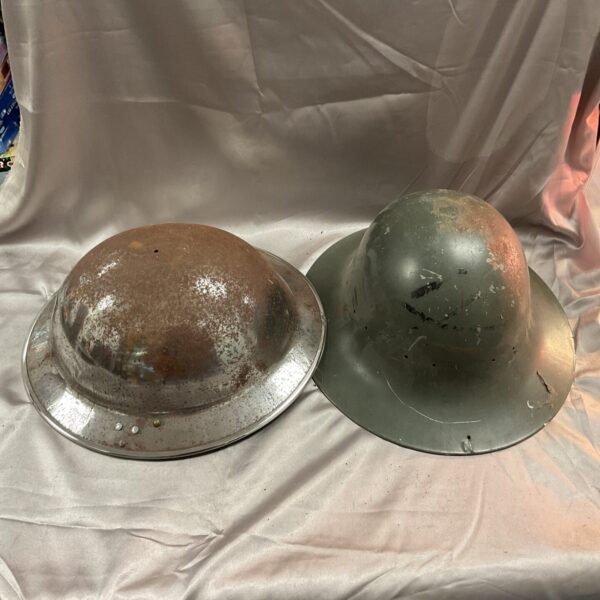 Vintage WWII chrome Tommy and Zuckerman military helmets for collectors.