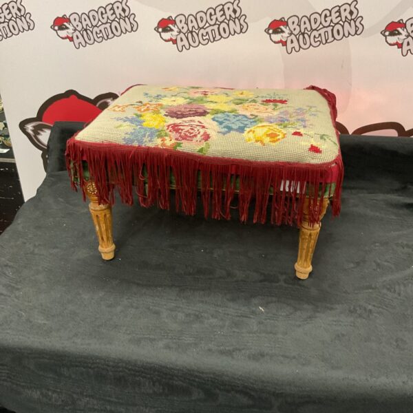Close-up of vintage embroidered footstool with floral pattern.