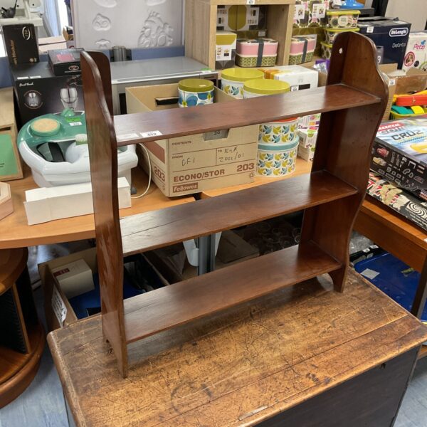 Vintage mahogany shelf unit with books and collectibles.