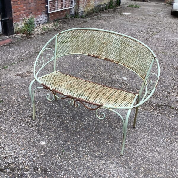 Vintage metal garden bench for restoration in a garden setting.