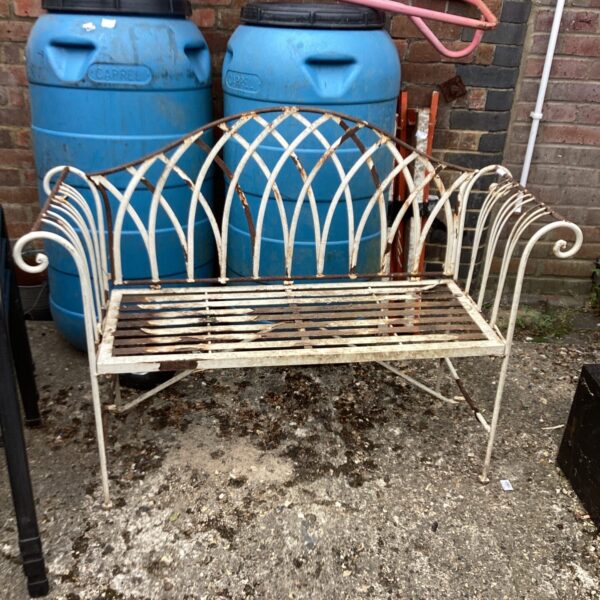Rustic vintage metal garden bench awaiting restoration in a garden.